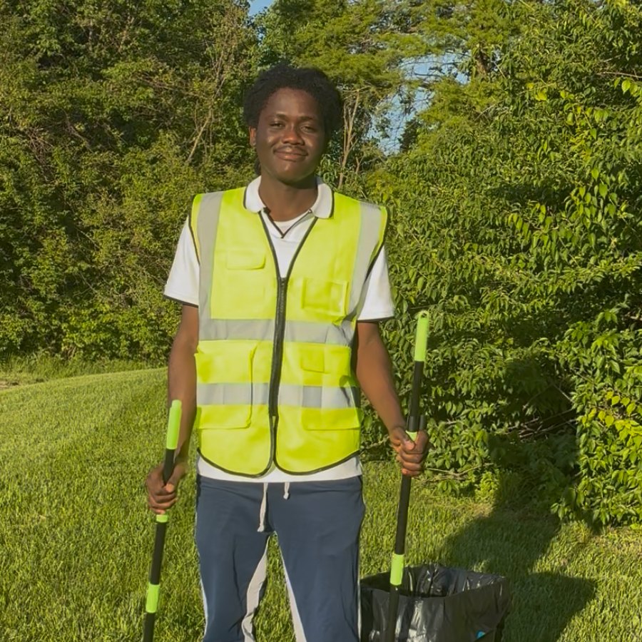 Geff, the owner of Geff's Pooper Scooper, standing in a yard in his work vest holding his scooping tools